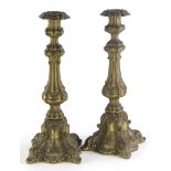A pair of continental brass candlesticks, each decorated in rococo style with scrolls, shells, etc.,