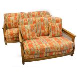 An Ercol elm and caned three seater sofa, and a matching two seat sofa, with geometric multicoloured