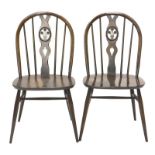 A pair of beech and elm Ercol dining chairs, each with a pierced wheelback and a solid seat, on