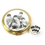 A 1960's powder compact, the lid inset with an image of the Beatles, and a Rolling Stones pin badge.