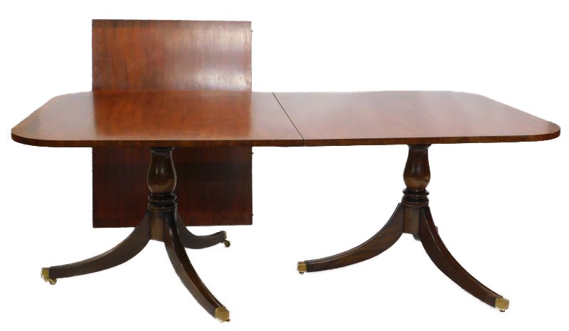 A mahogany two pillar dining table in Regency style, the rectangular top with a crossbanded border