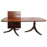 A mahogany two pillar dining table in Regency style, the rectangular top with a crossbanded border