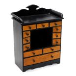 A small ebonised and mahogany table top cabinet, with a raised back and various drawers, each with