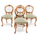 A set of four Victorian walnut balloon back dining chairs, each with a flower carved crest, and a