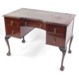 An early 20thC mahogany kneehole desk, the concave fronted top inset with tooled brown