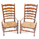 A pair of oak six rung ladder back country chairs with rush seats, raised on turned legs united by