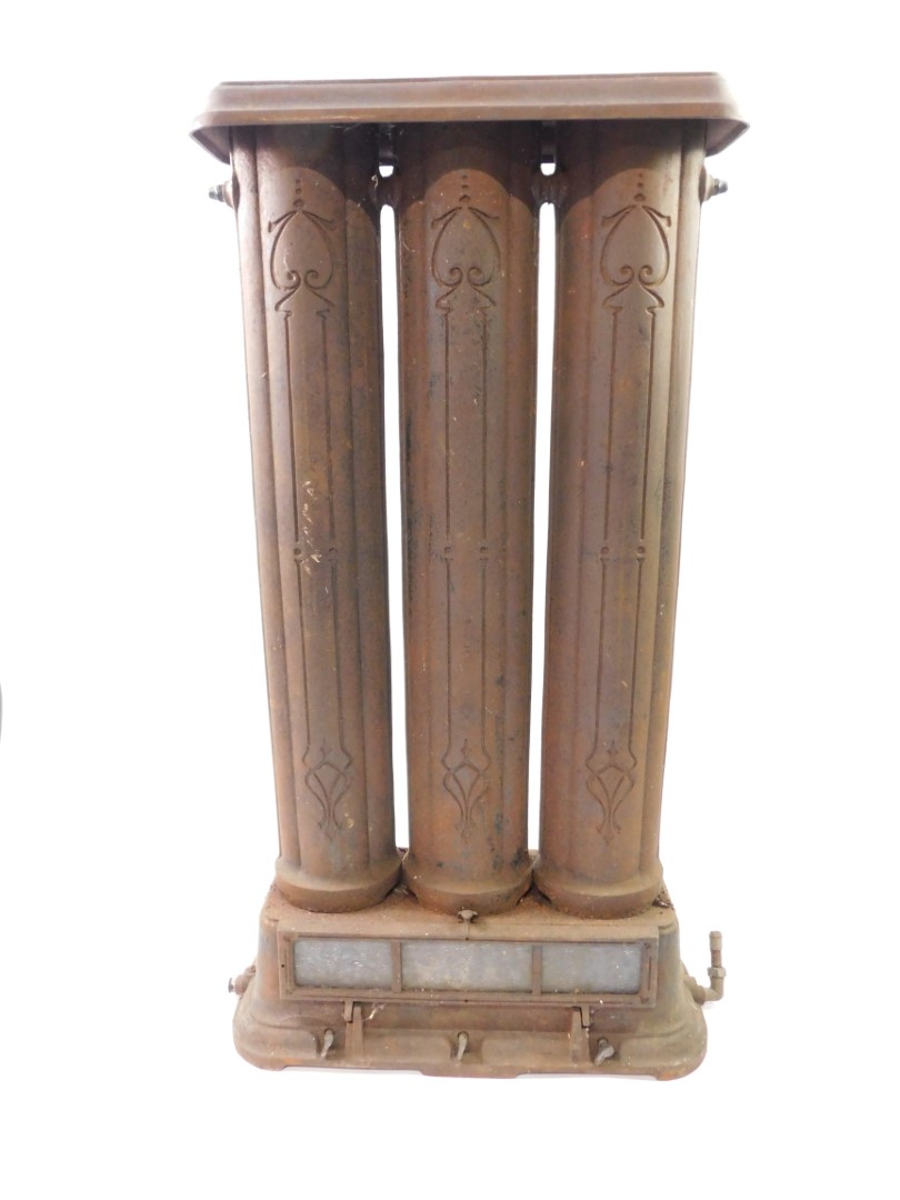 A Victorian cast iron oil and gas radiator, of three column form, above a glass paneled drop