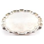A George V silver pie crust salver, presentation engraved, raised on three leaf cast ball feet,