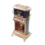 A Petrolux late 19thC black tin and brown enamel stove, with copper burner and glass chimney,