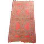 A Caucasian rug, red ground decorated with three central medallions within geometric borders,