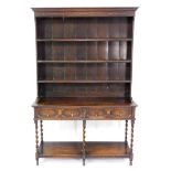 A 17thC style oak dresser, the outswept pediment over three shelf plate rack, above two panelled