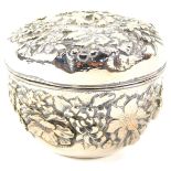 A Chinese cylindrical silver box and cover, repousse decorated with mixed flowers, four character