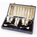 A George VI silver three piece condiment set, with blue glass liners, and spoons, cased, Hukin &