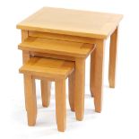 A light oak nest of occasional tables, raised on square legs, largest 50cm high, 54cm wide, 42cm