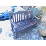 A teak garden bench, with floral carved back rail.