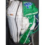 A set of cricket whites in a Gunn and Moore bag, together with shin pads.