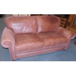 A brown leather two seater sofa, raised on bun feet, 199cm wide.