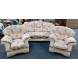 A three piece suite, upholstered in a beige and floral patterned chenille fabric.