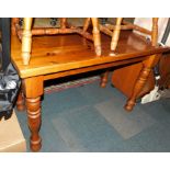 A rectangular pine kitchen table raised on turned legs, 76cm high, 122cm wide, 62cm deep.