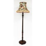 An oak standard lamp, with floral shade, on a part fluted stem, on a circular layered base, 70cm