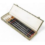A cased calligraphy set, with five Chinese calligraphy brushes in a green storage box.