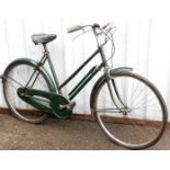 A Sturmey Archer geared vintage ladies bicycle, with a green frame on a black leather seat.