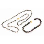 A blackened pearl single strand necklace and bracelet set, on a yellow metal ball clasp stamped 750,