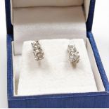 A pair of diamond drop earrings, each with graduated round brilliant cut diamonds, in claw