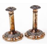 A pair of old Sheffield plate candlesticks, each with rococo style decoration on tapered bases,