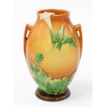 An early 20thC Roueville art pottery vase, on a terracotta coloured base, with dandelion decoration,
