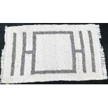 A large wool rug, with cream overall design and grey central decoration, on light tassel thread