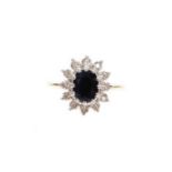 A 9ct gold cluster ring, with central dark blue stone surrounded by various cz stones, on a raised