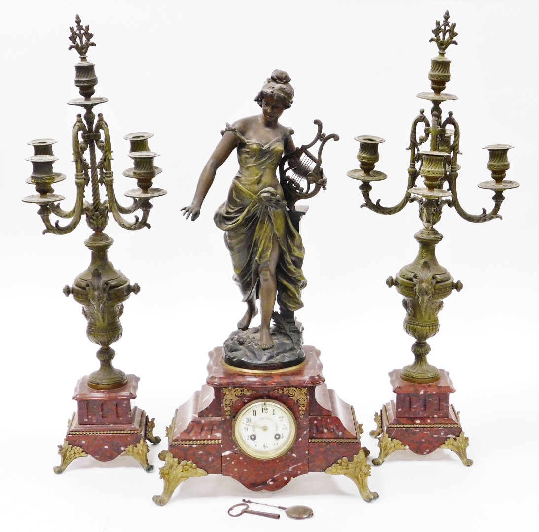 A late 19thC French clock garniture, with mantel clock, on a red marble base with a gilt spleter