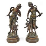 A pair of reproduction plaster figures, each of maidens with children, on a wooden base, stamped