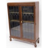 An oak display cabinet, with two astragal glazed doors, and three plain shelf interior, on carved