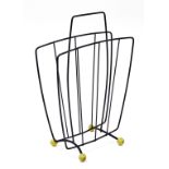 A 1960's/70's magazine rack, with metal design, on yellow ball feet, with carrying handle, 44cm