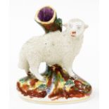 A late 19thC Staffordshire style figure of a sheep, on a brown mottle base, unmarked, 14cm high.