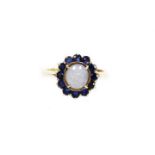 A moonstone and sapphire cluster ring, the central oval cut moonstone set in four claw setting