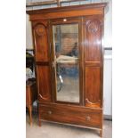 An Edwardian mahogany wardrobe, the moulded dentil top above a central mirrored panel and two carved
