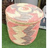 A multicoloured woven large storage basket, with red and black woven design and mirrored centre.