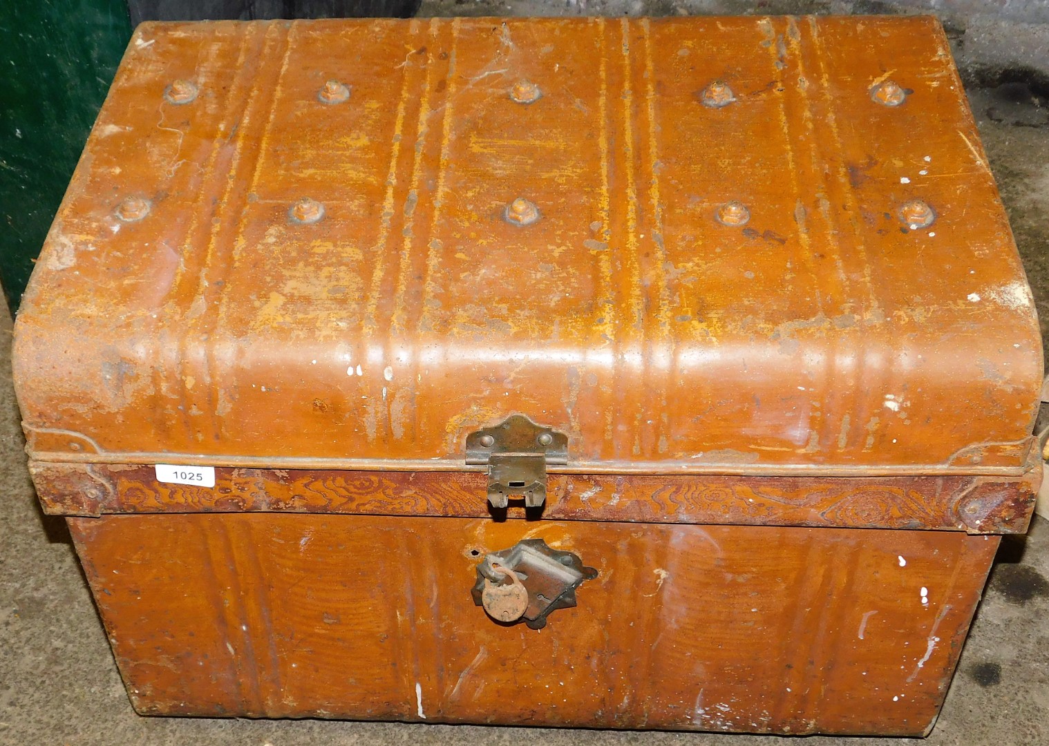 A tin trunk, with a domed top and padlock.