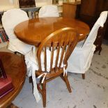 An oak finished circular dining table and four associated chairs.