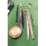 A copper warming pan and various umbrellas and hiking sticks.