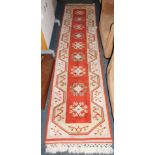 A red and cream wool runner, with a row of nine central medallions, 286cm x 68cm.