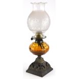 A late Victorian cast iron oil lamp, with brass fitting, amber tinted reservoir and parcel gilt