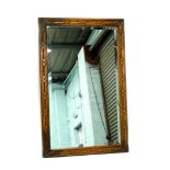 A carved oak wall mirror, with a rectangular bevelled plate, 104cm x 67cm.