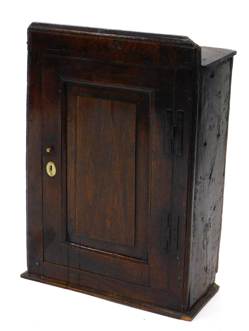 A late 17th/early 18thC oak wall cupboard, the top with a moulded edge above a single panelled door,