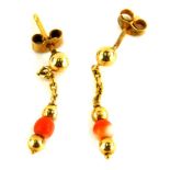 A pair of coral drop earrings, each with fine link chain and gold ball and gold coral drop design,