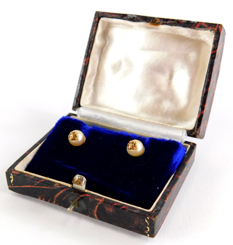 A pair of cultured pearl earrings, each with single pearl and gold six point flower end, on screw on