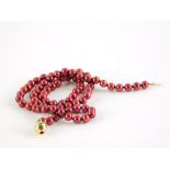 A cultured pearl single strand necklace, with red glossy finish, on a yellow metal ball clasp,